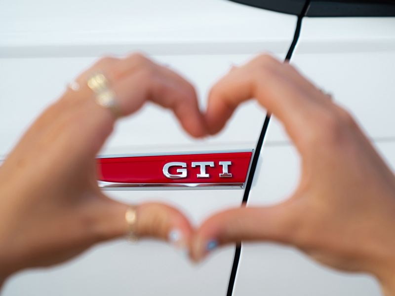 Two hands in the shape of a heart around a “GTI” logo