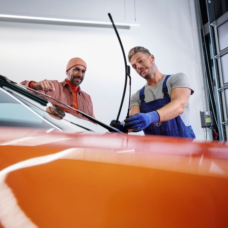A VW service employee and a customer inspect a VW windshield wiper