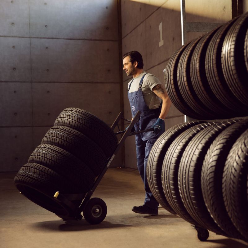 Ein VW Servicemitarbeiter transportiert einen Satz Reifen
