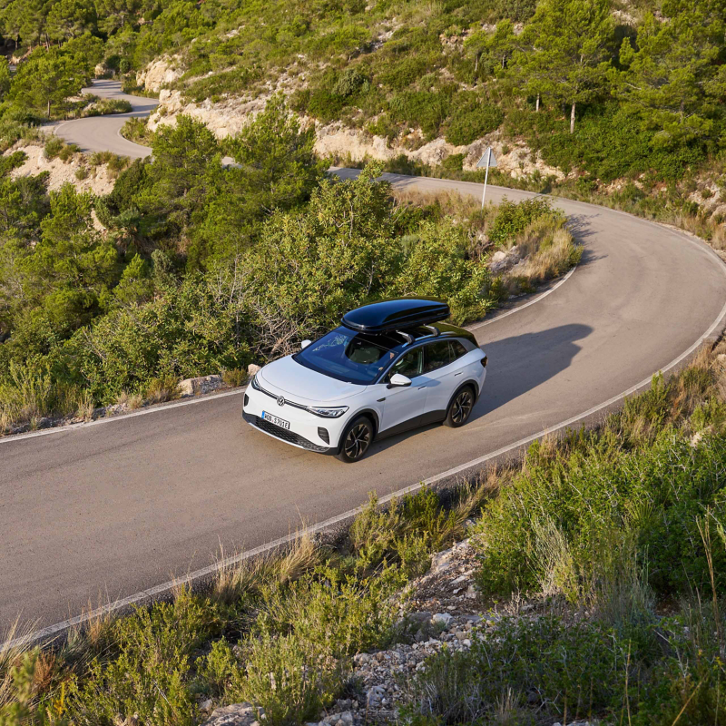 VW Elektroauto mit Dachbox fährt auf einer Landstraße