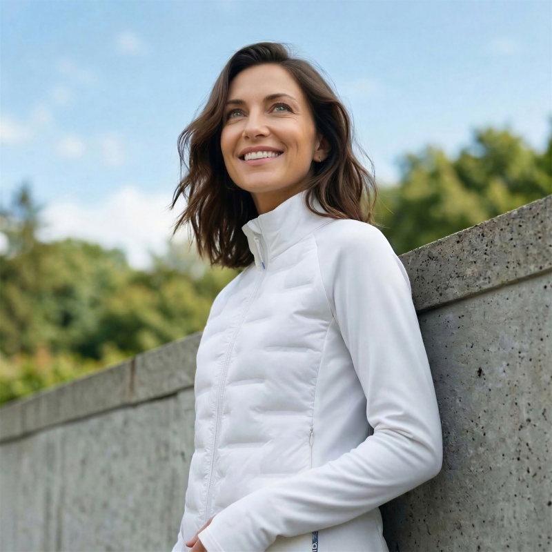 Frau mit Hybridjacke aus der ID. Kollektion lehnt an Wand