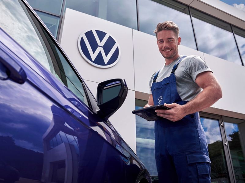 Filtre à air d’origine Volkswagen dans un atelier de réparation avec un employé de VW services en arrière-plan – pièces de rechange pour votre voiture