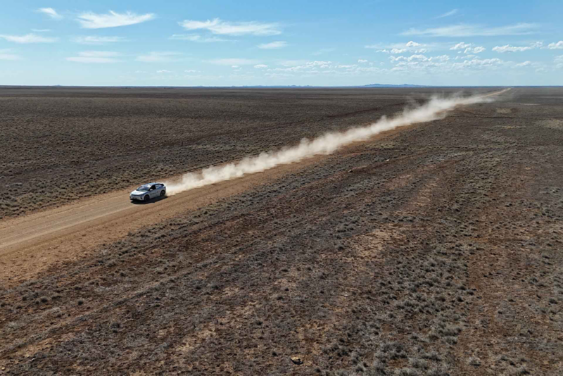 Ariel view of ID.4 driving on desert road with dust plume
