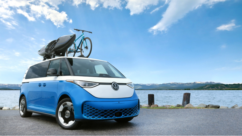 Hombre con chaleco naranja de VW de pie junto al vehículo Volkswagen.
