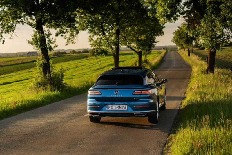 Niebieski Volkswagen Arteon jedzie drogą.