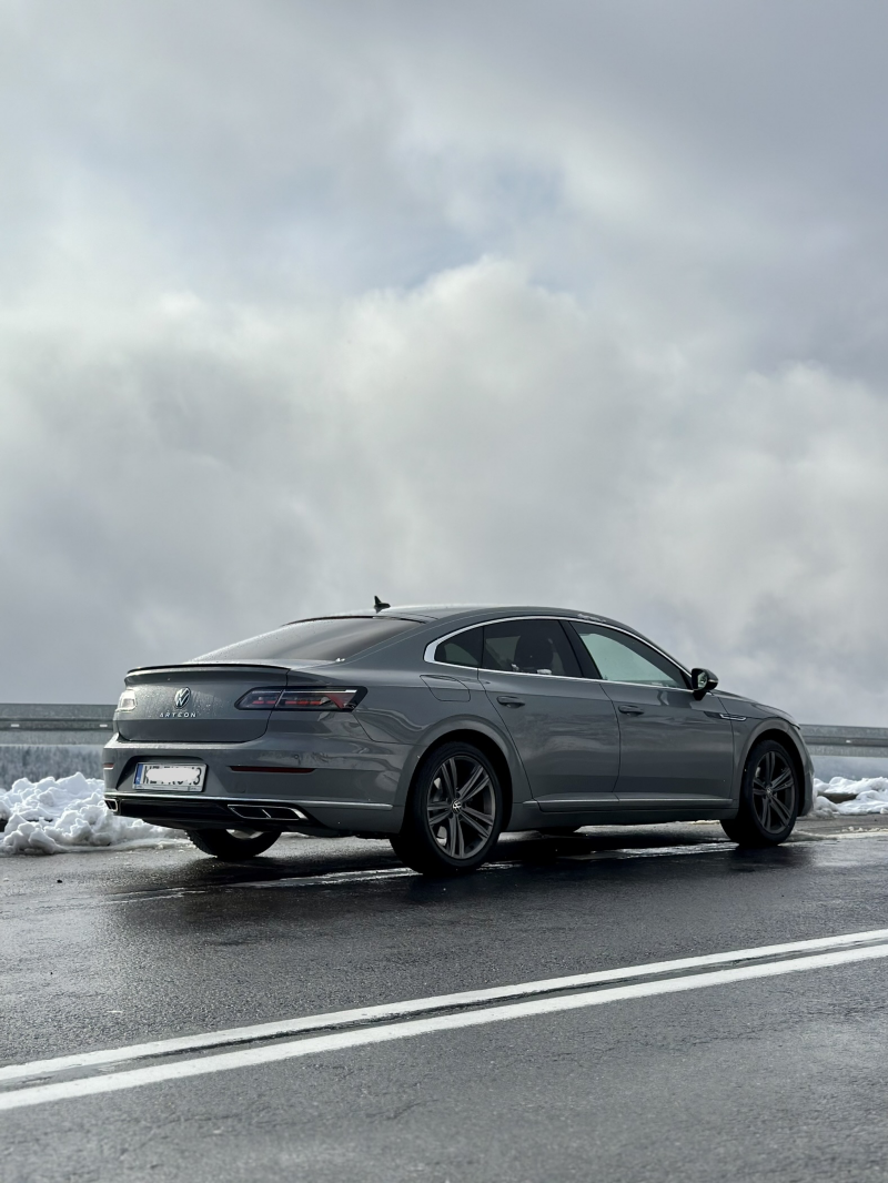 Volkswagen Arteon jedzie drogą na tle zimowego krajobrazu.