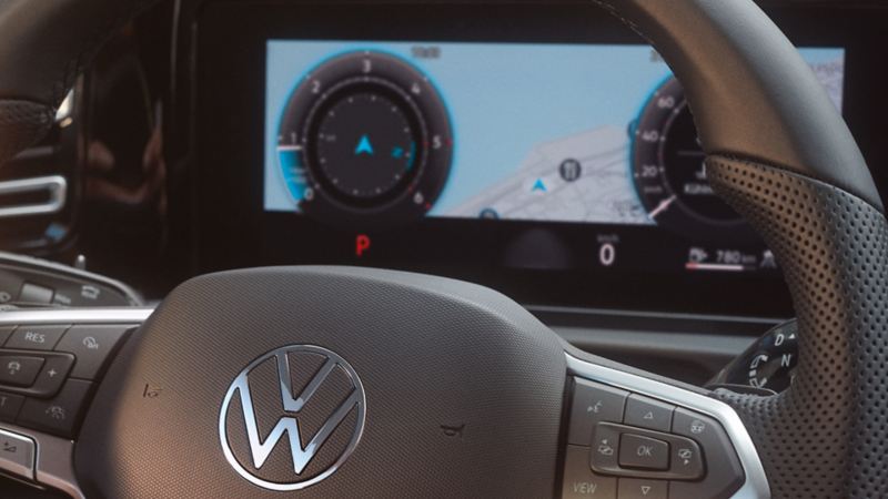 Detailed view of the cockpit in a VW Tiguan. Two hands clasp the steering wheel.