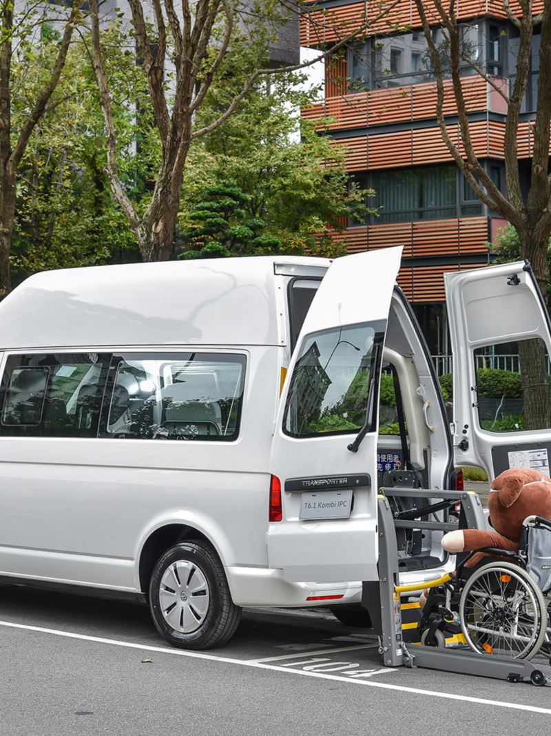 香草白色的T6.1 Kombi停在路邊後廂門敞開，有電動輪椅升降梯可以'方便有輪椅需求的乘客