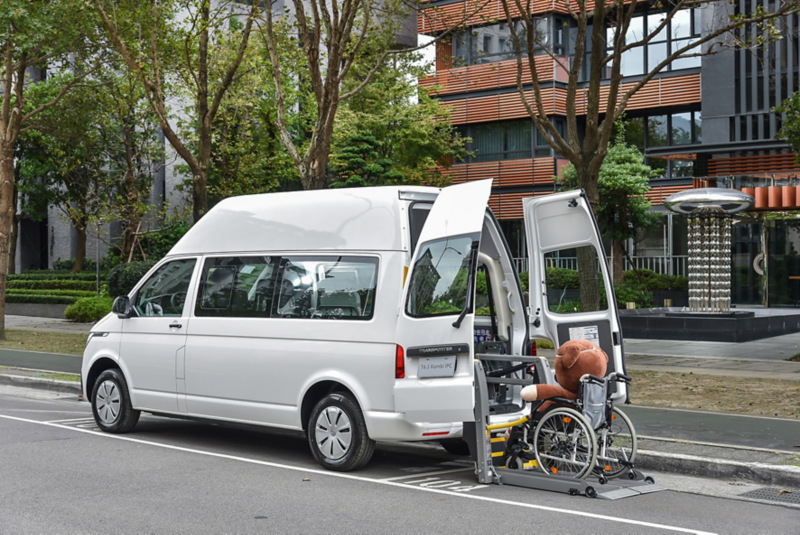 香草白色的T6.1 Kombi停在路邊後廂門敞開，有電動輪椅升降梯可以'方便有輪椅需求的乘客