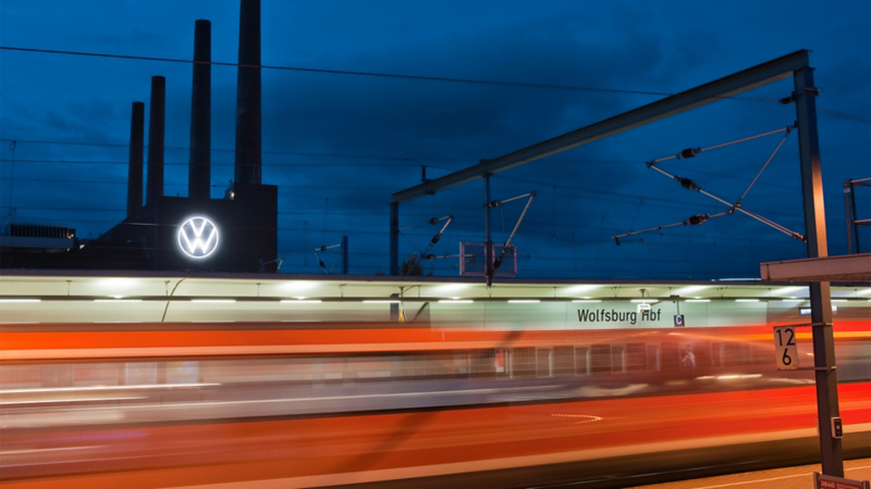 Vorbeifahrender Zug vor dem Volkswagen Werk Wolfsburg bei Nacht