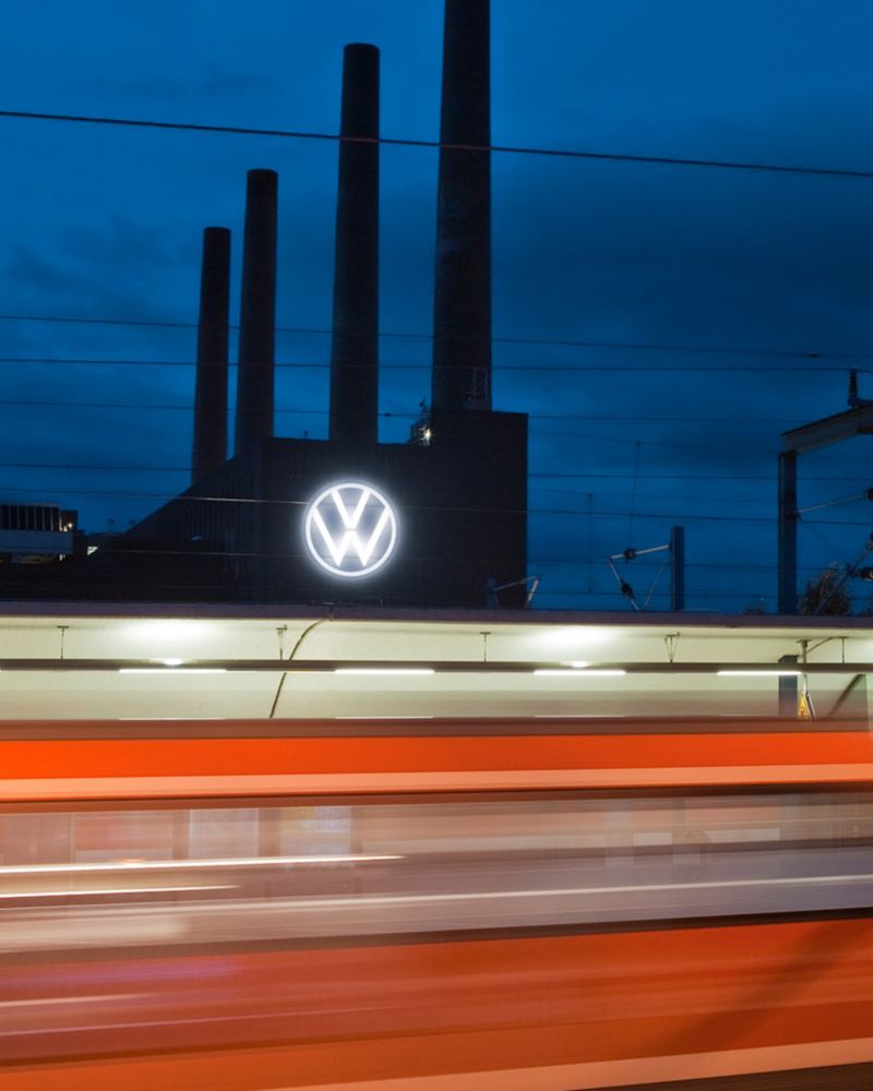Vorbeifahrender Zug vor dem Volkswagen Werk Wolfsburg bei Nacht