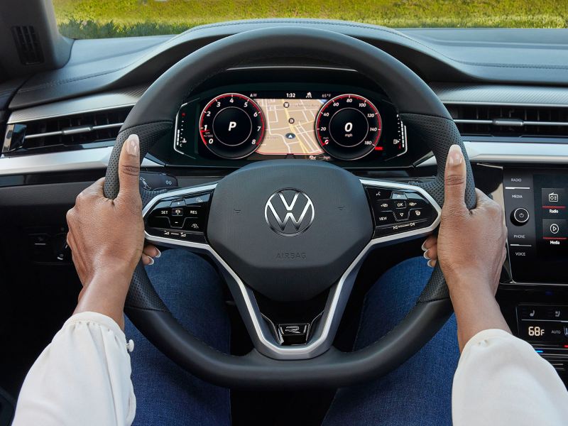 Une femme tient le volant d’une Arteon de Volkswagen à deux mains. lien vers la page des essais de conduite VW
