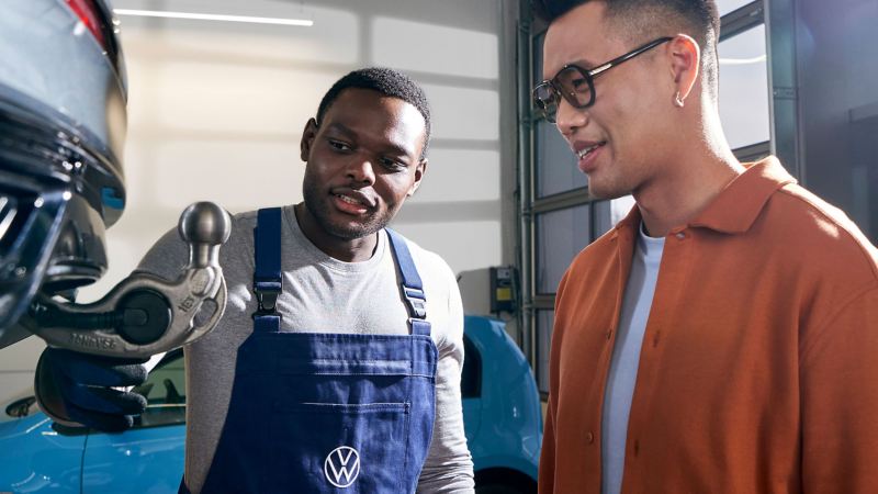 A VW service employee and a customer look at a ball coupling
