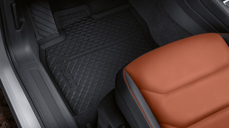 A practical VW all-weather floor mat in the footwell of a car