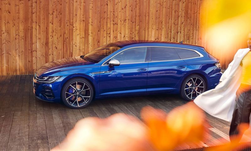 A blue VW Arteon R Shooting Brake parked in front of a wooden wall