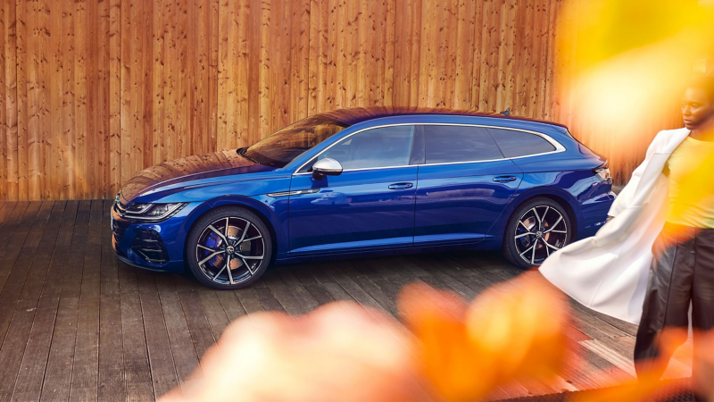 A blue VW Arteon R Shooting Brake parked in front of a wooden wall