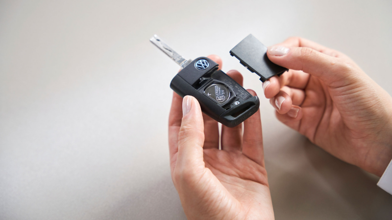 Kundin hält geöffneten VW Autoschlüssel mit Gerätebatterie