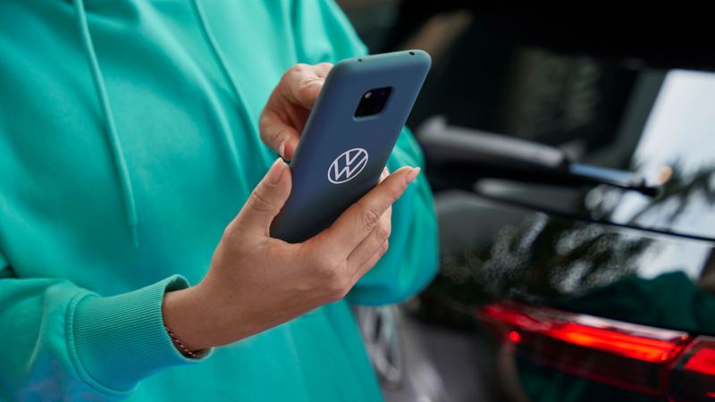 En kvinde tjekker EU-overensstemmelseserklæringer vedr. VW's bærbare batterier på en smartphone.