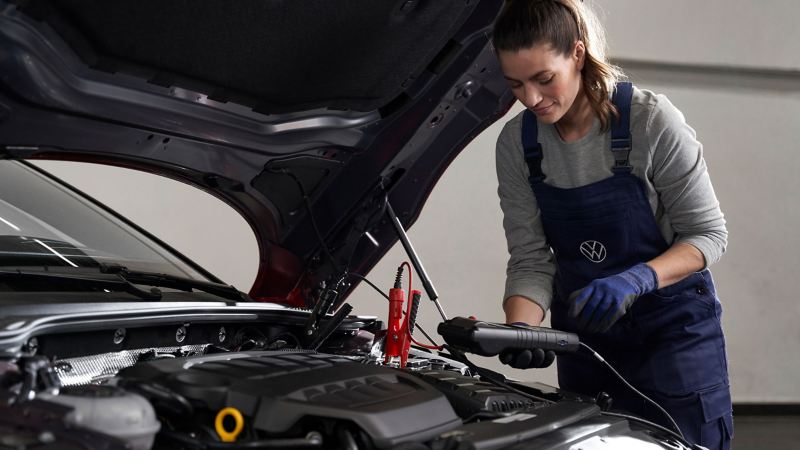A VW service employee checks the battery inside of a VW car
