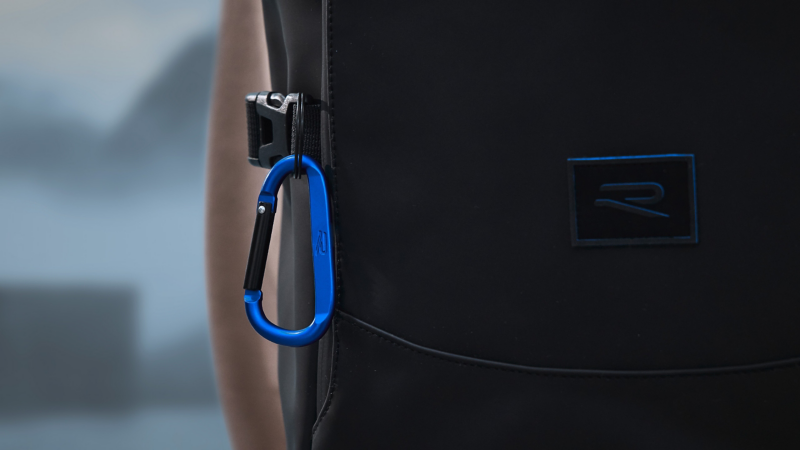 Schwarzer Schlüsselring mit blau-schwarzem Karabiner, der an einem Rucksack aus der R-Kollektion befestigt ist