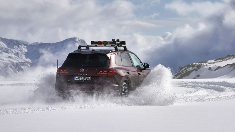 Een VW Touareg rijdt op een besneeuwde weg; er dwarrelt sneeuw op de auto