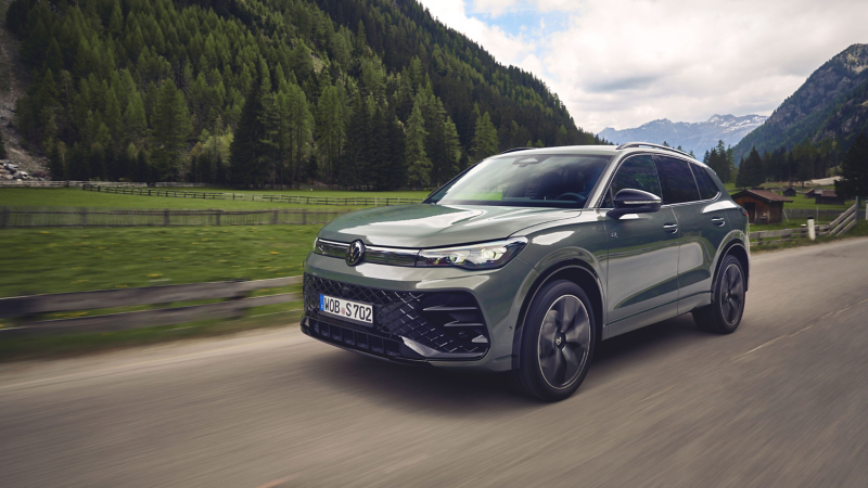 VW Tiguan su una strada di campagna, con montagne sullo sfondo.