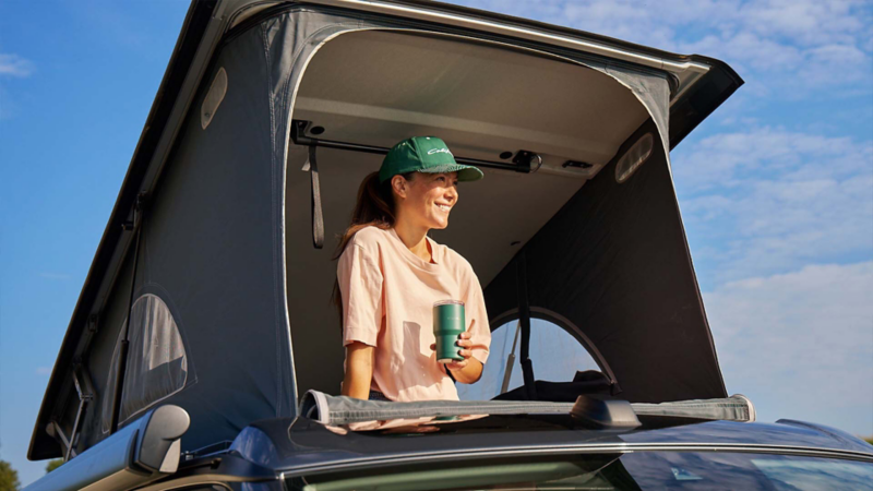 Photo showing a woman sitting in the bedding area of a VW California. 