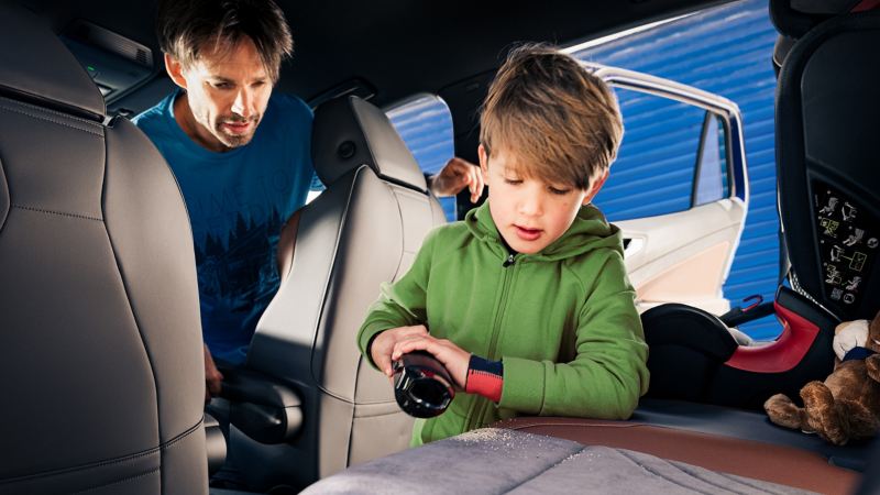 Un père et son fils passent ensemble l’aspirateur sur les sièges de leur Volkswagen
