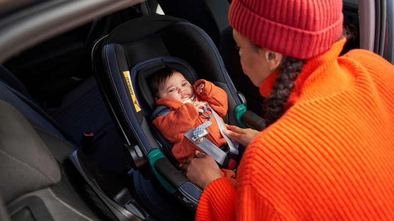 En kvinde spænder en baby fast i et autostol