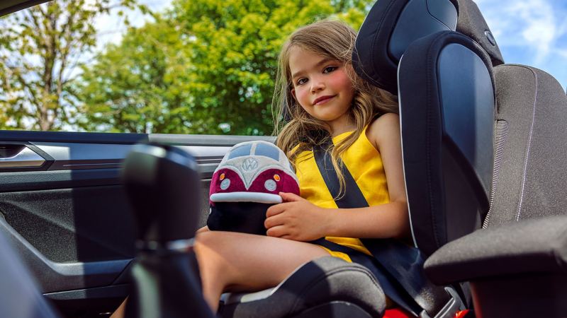 Un enfant est assis dans un siège enfant des Accessoires VW