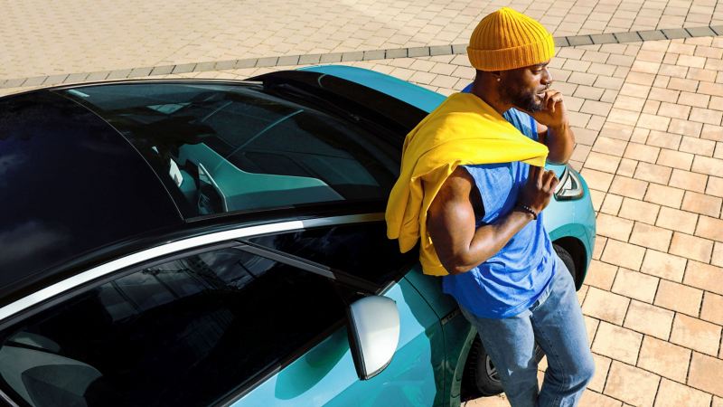Ένας άνδρας στέκεται δίπλα από ένα ID. και καλεί την οδική βοήθεια Volkswagen.