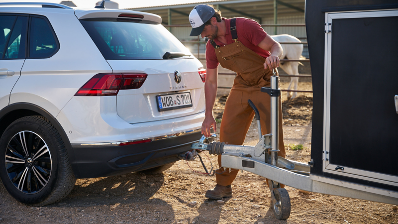 Mann löst Anhänger von der Anhängevorrichtung eines VW Tiguan