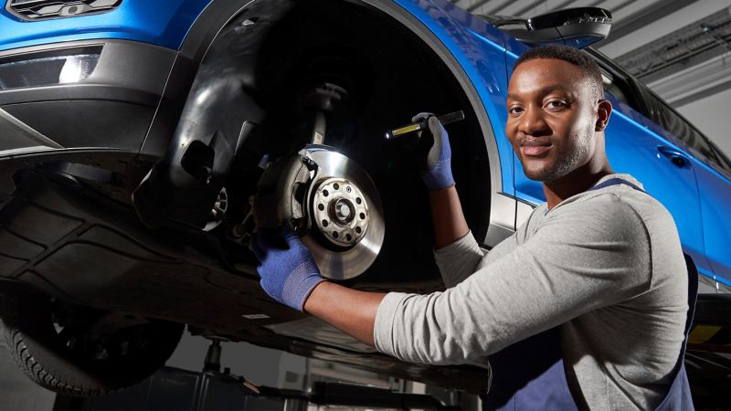 VW service employee inspects the brakes of a VW car – Economy Service