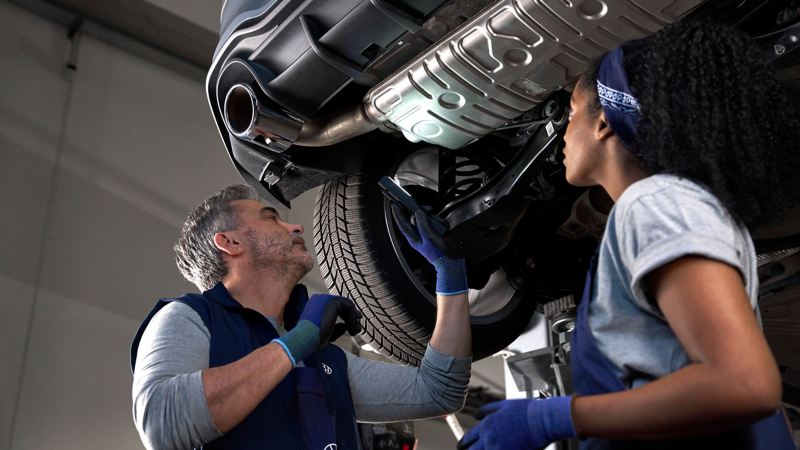 Deux collaborateurs d’atelier Volkswagen inspectent le système d’échappement d’une voiture Volkswagen