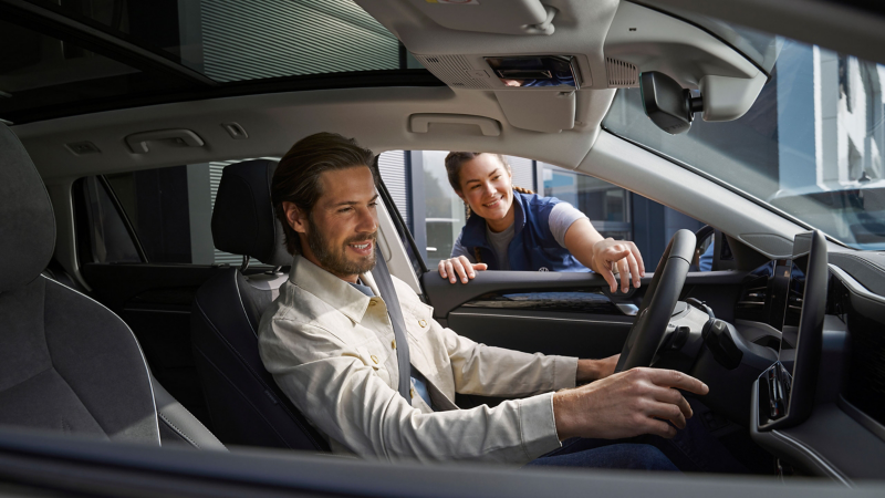 VW Servicemitarbeiter zeigt Kunde neue Funktionen im VW Auto