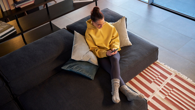 A young woman checks her smartphone for the latest ID. software updates, a dog sits next to her