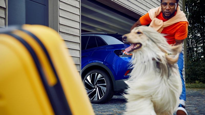 Een man met een hond, op de achtergrond een geparkeerde ID.4 in een garage