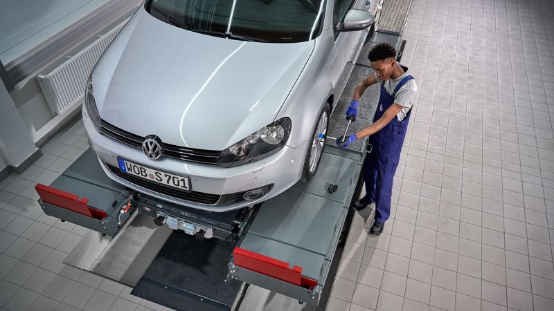 VW service employee tightens screws on the wheel of a VW Golf 6