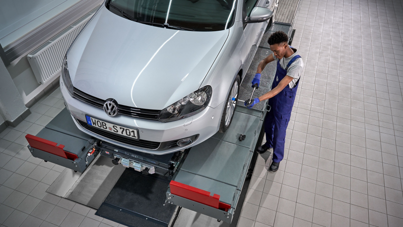 VW service employee tightens screws on the wheel of a VW Golf 6