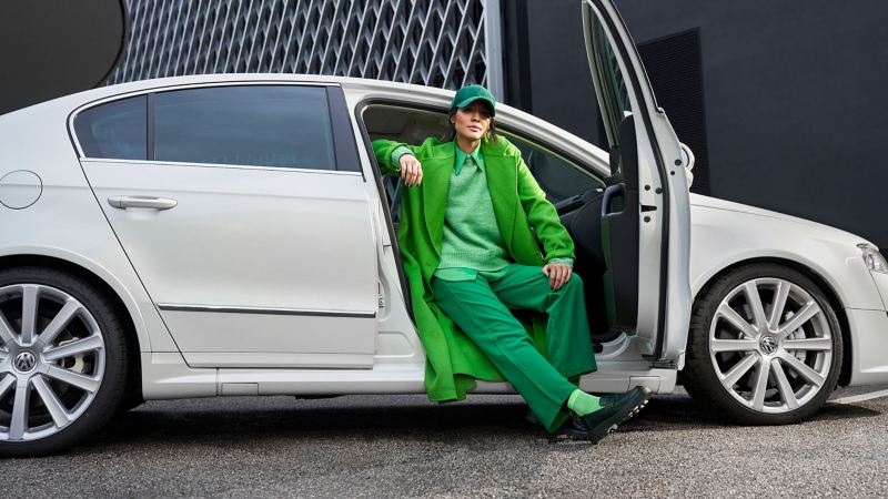 Eine in grün gekleidete Frau sitzt auf dem Beifahrersitz eines weißen VW Passat R36