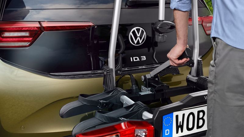 Une personne installe un porte-vélos Compact II des accessoires VW sur le dispositif d’attelage d’une VW ID.3