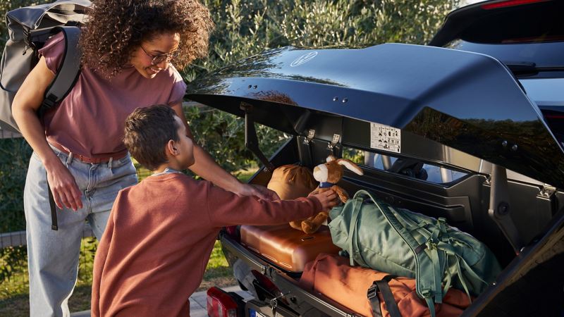 Une mère et son fils chargent un coffre arrière des accessoires VW