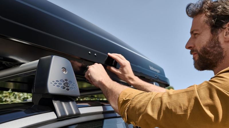 Man fixates roof box by VW Accessories on a VW ID. 7