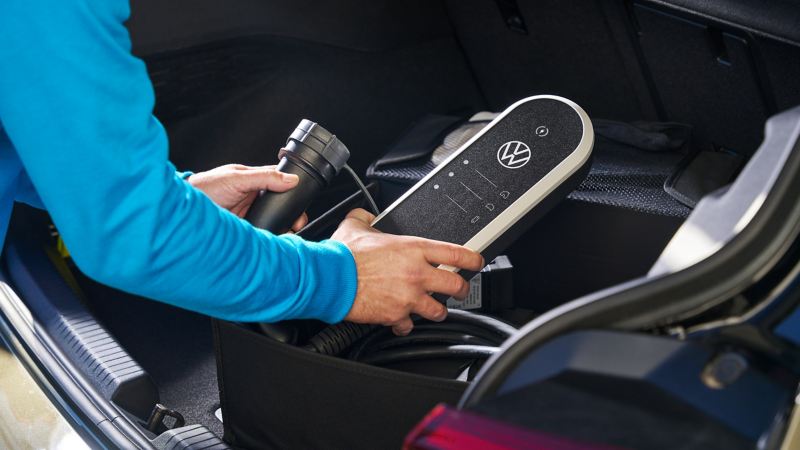 Iemand haalt de ID. Charger Travel Basic van VW-accessoires uit de plooibox voor laadkabels