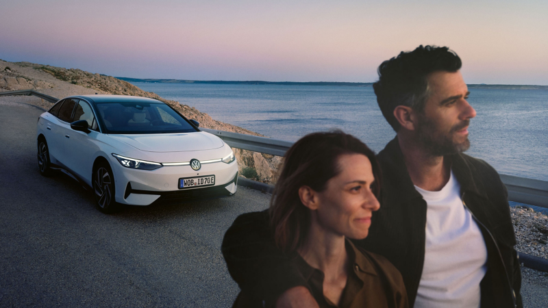 Paar neben VW E-Auto auf Straße beobachtet Sonnenuntergang