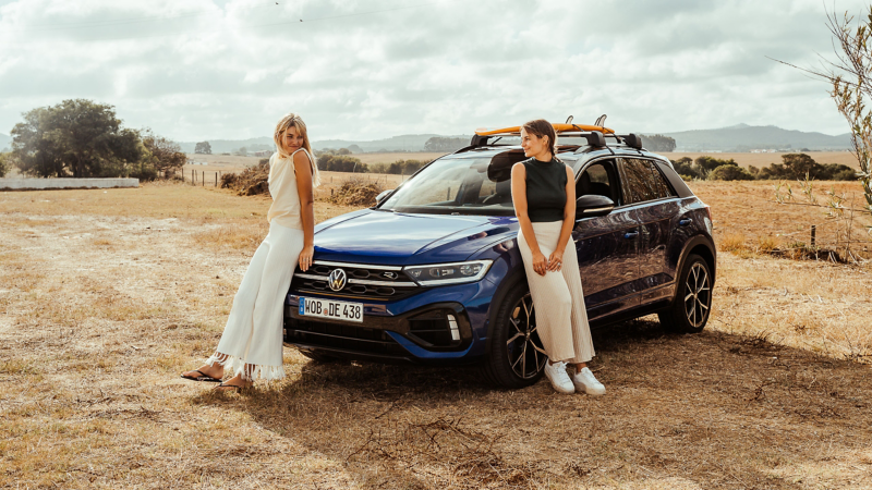 Zwei Frauen lehnen sich an ihren VW T-Roc R an