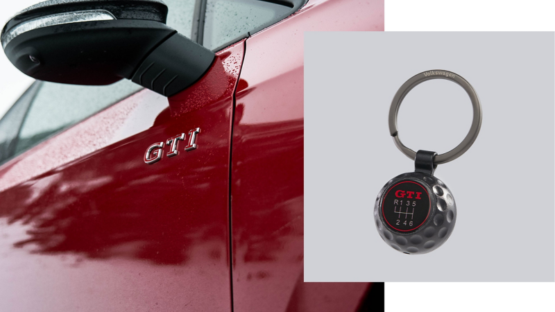 Llavero GTI sobre un primer plano del lateral del pasajero de un VW Golf GTI rojo, con finas gotas de lluvia y el logotipo GTI.