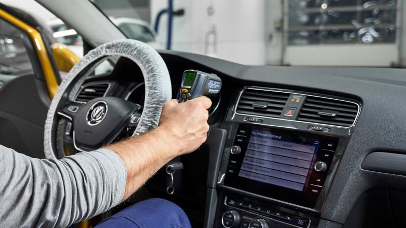 Ein VW Servicemitarbeiter prüft die Klimaanlage in einem Auto – VW Service