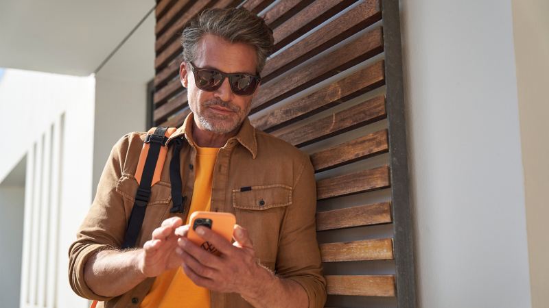 Mann mit Sonnenbrille bucht einen Driving Experience Termin am Smartphone