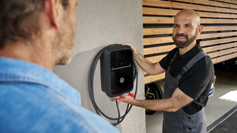 Zwei Männer neben angebauter Wallbox für VW E-Auto